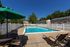 Inviting apartment community pool area with sun loungers, green parasols, and a clear blue sky backdrop, perfect for relaxation.