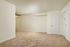 Spacious, light-filled living area with plush carpeting and modern ceiling fan, perfect for relaxation and entertaining.