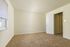 Inviting bedroom with plush carpet, large window for natural light, and neutral walls, perfect for relaxing.