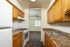 Inviting kitchen with warm wooden cabinets, sleek appliances, and a view into a bright living area, perfect for modern living.