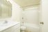 Bright and elegant bathroom featuring a modern white vanity, pristine tiles, and a relaxing bathtub.
