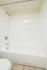 Bright, immaculate bathroom featuring a pristine white bathtub and sleek tiled walls, perfect for a relaxing retreat.