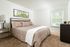 Bright and inviting bedroom with a plush quilted bed, stylish decor, and a serene window view.