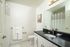 Modern bathroom with white cabinetry, a sleek black countertop, and elegant fixtures, featuring a large mirror and contemporary shower curtain.