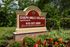 Charming outdoor sign for Gulph Mills Village Apartments surrounded by vibrant greenery and colorful flowers.