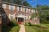 Charming brick apartment building with lush greenery and inviting red door entrance under clear blue skies.