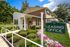 Charming leasing office surrounded by vibrant landscaping and blooming flowers, showcasing welcoming curb appeal.