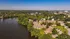 Aerial view of a serene residential community surrounded by lush greenery and a tranquil lake, offering a peaceful and picturesque living environment.