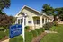 Charming leasing office with an inviting porch, surrounded by lush greenery and vibrant flowers, symbolizing a welcoming community environment.