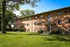 Charming brick apartment building with lush green lawns and ample natural light under a clear blue sky.
