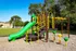 Vibrant playground featuring colorful slides, climbing structures, and monkey bars set in a lush green park.