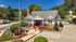 Charming leasing office with inviting landscaping and adjacent pool surrounded by lush greenery, perfect for a welcoming community atmosphere.
