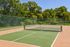 Vibrant outdoor tennis court surrounded by lush greenery, offering a perfect setting for sports enthusiasts.