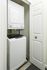 Compact laundry nook featuring a convenient stacked washer and dryer set behind a white door.