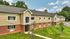 Charming and modern two-story apartment building with brick and siding facade, set amidst lush greenery and a well-maintained lawn.
