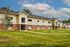 Charming apartment complex featuring modern architecture with a blend of brick and siding, surrounded by lush green lawns and young trees under a clear blue sky.