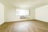 Bright, spacious room with sleek hardwood flooring and large window filling the space with natural light.