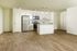 Spacious modern kitchen with elegant white cabinetry, stainless steel appliances, and chic pendant lighting over a central island, set on polished wood flooring.