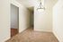 Bright hallway with plush carpet and modern light fixture leading to a room with hardwood floor, ideal for stylish living spaces.