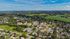 Scenic aerial view of a vibrant suburban community surrounded by lush greenery and expansive fields, offering serene living with convenient access to nature.