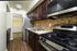 Modern kitchen with sleek stainless steel appliances, rich dark wood cabinetry, and elegant hardwood flooring.