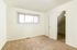 Bright and cozy room with fresh carpet, white walls, and a window with vertical blinds, perfect for personalizing your ideal living space.