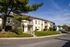 Charming apartment complex with cozy front porches and lush greenery under a clear blue sky.