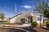 Charming leasing office surrounded by vibrant landscaping and a clear blue sky.