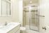 Modern bathroom with sleek white vanity, elegant tiled shower, and contemporary fixtures.