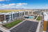 Modern apartment complex with vibrant facade, lush green space, and inviting pool, framed by scenic mountain views under a bright blue sky.