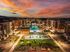 Luxurious apartment complex with a stunning central pool area, beautifully lit at sunset, surrounded by modern buildings and lush palm trees.