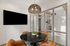 Chic modern dining area with a black marble table, elegant pendant lighting, and stylish glass partition.
