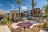 Luxurious apartment courtyard with a sparkling pool, cozy seating areas, and elegant palm trees under a bright blue sky.