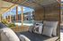 Luxurious poolside lounge area with plush seating and a stunning view of modern apartment buildings under a bright blue sky.