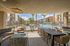 Luxurious outdoor lounge area with modern seating overlooking a stunning pool, surrounded by stylish apartment buildings under a bright blue sky.