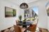 Chic dining area with a round marble table, stylish leather chairs, and a large window offering a view of modern apartment buildings.