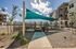 Modern apartment exterior with stylish shade sails, landscaped garden, and spacious pathways under a bright blue sky.