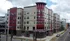 Contemporary apartment building with a striking red and beige facade seen from the street view.