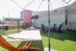Chic outdoor lounge area featuring a hammock, patio chairs, and sun umbrella on a green turf surface.