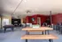 Contemporary lounge and recreation space with a pool table, seating area, and bar stools, set against a vibrant red accent wall.