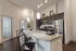 Modern kitchen with sleek dark cabinetry, stainless steel appliances, and a spacious granite island with pendant lighting.