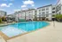 Luxurious modern apartment complex with a sparkling swimming pool and stylish poolside seating.