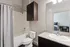 Modern bathroom with elegant dark wood cabinetry, pristine white bathtub, and sleek granite countertop.
