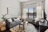 Chic and cozy living room featuring a stylish gray sofa, modern art piece, and large window with natural light.