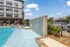 Modern apartment complex featuring a luxurious pool with a stylish waterfall, sun deck, and vibrant outdoor lounge area.