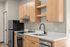 Modern apartment kitchen featuring sleek wooden cabinets, stainless steel appliances, and an elegant black faucet.