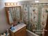 Charming bathroom with butterfly-themed shower curtain and warm wooden cabinetry, in Westridge One Bedroom apartment.
