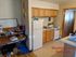 Cozy Westridge One Bedroom apartment featuring a compact kitchen with wooden cabinets, a refrigerator, and a small stove, adjacent to a functional workspace.
