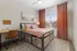 Bright and cozy bedroom with stylish bed, vibrant red curtains, and ample natural light, perfect for relaxation and study.