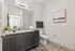 Bathroom with vanity in Auburn student housing. Modern bathroom featuring sleek granite countertops, elegant dark cabinets, and a serene artwork on the wall.